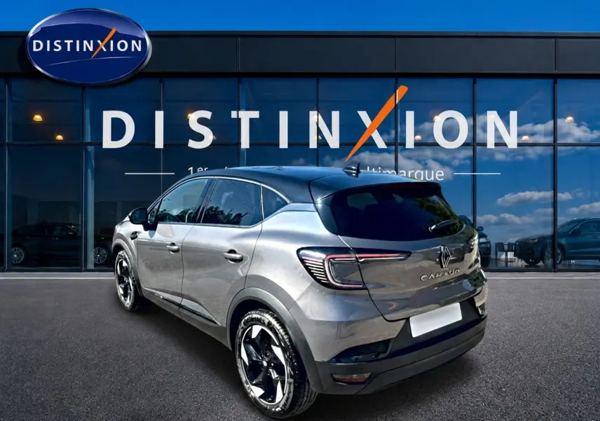 Renault Captur gris cassiopée en 3/4 arrière droit, avec jantes alu et toit noir devant vitrine Distinxion.