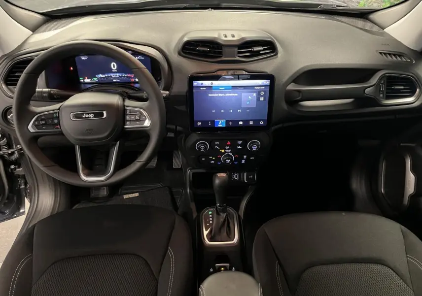 Intérieur Jeep Renegade 2024 vu de face, tableau de bord noir avec écran tactile central et volant multifonction.