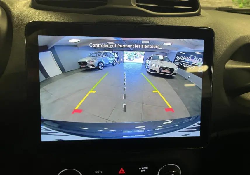 Vue arrière sur l'écran de caméra de recul montrant un Jeep Renegade gris stationné en intérieur avec marquages de guidage colorés.