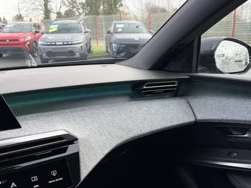 Vue intérieure côté passager du tableau de bord gris clair et noir du Peugeot 3008 électrique 2024 avec détails texturés et sortie d'air moderne.