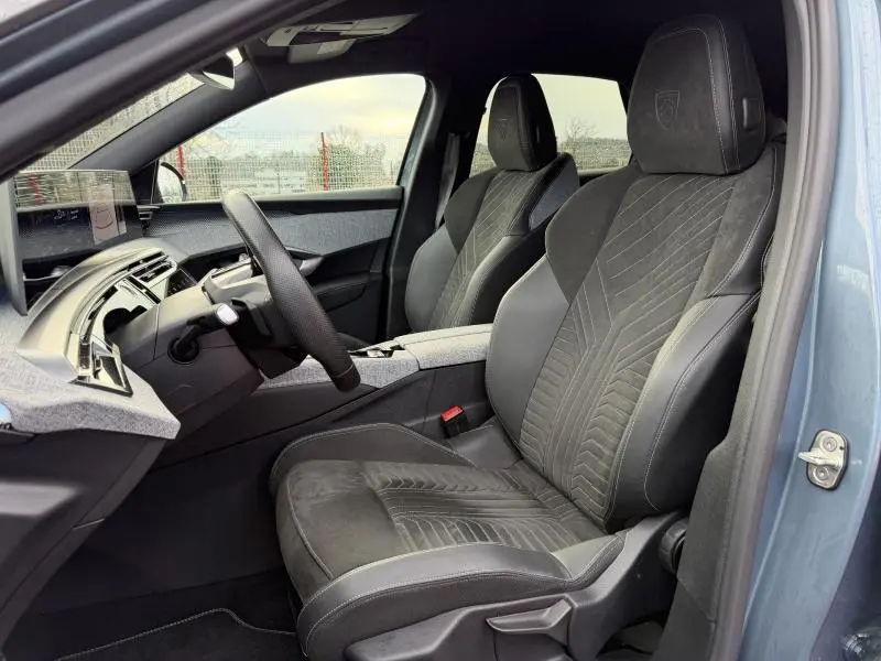 Vue intérieure côté conducteur du Peugeot 3008 GT électrique 2024 bleu, sièges en Alcantara et cuir avec logo Peugeot brodé.