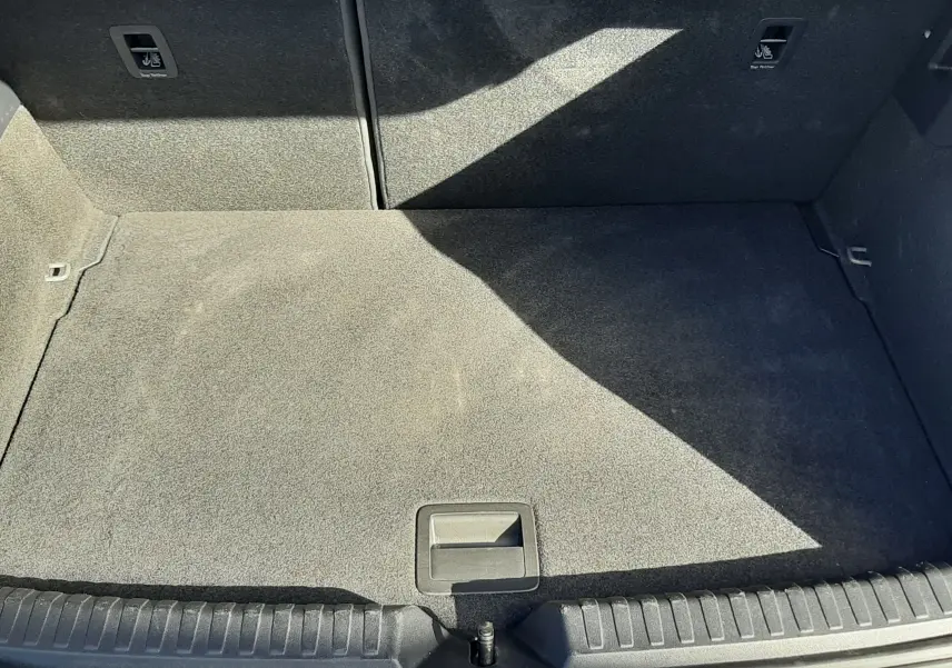 Coffre ouvert vu de dessus d'une Audi A1 Sportback 30 TFSI gris Chronos avec intérieur noir et tapis de coffre propre.