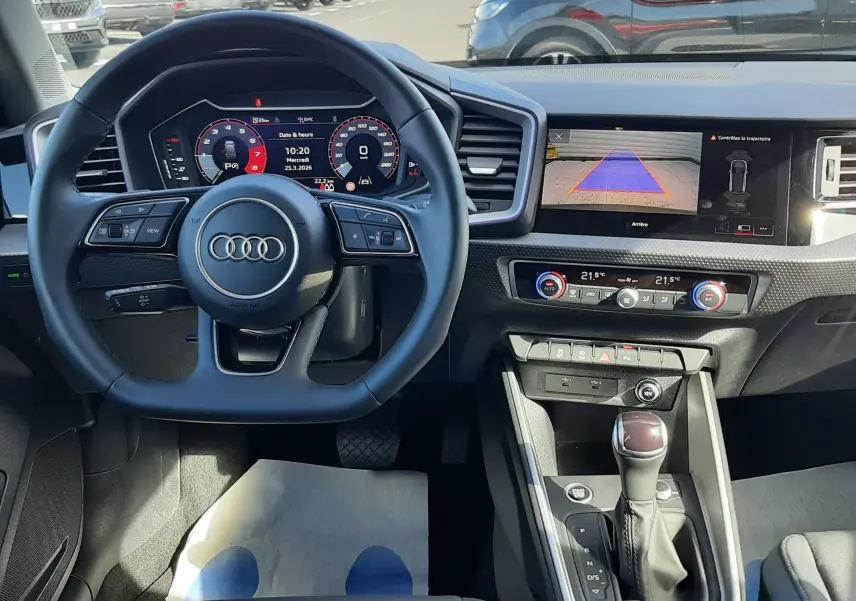 Vue intérieure de l'Audi A1 Sportback 2025, tableau de bord et volant cuir sport avec écran multimédia et caméra de recul.