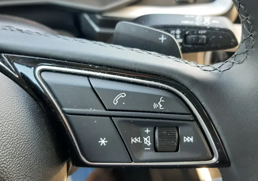 Gros plan sur les commandes multifonctions du volant cuir noir de l'Audi A1 Sportback 2025, finition S-Line.