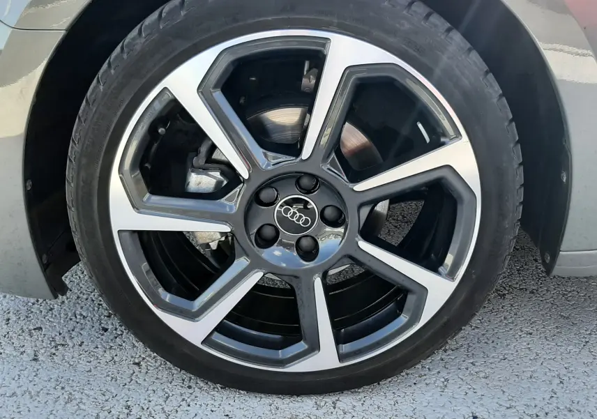 Gros plan sur la jante alu 18 pouces bicolore en hélice d'une Audi A1 Sportback gris Chronos, roue avant droite.