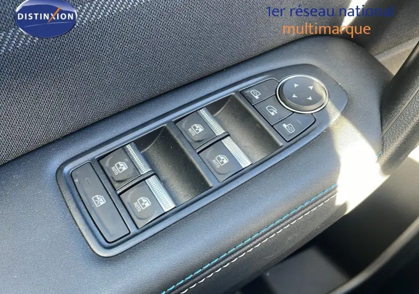 Gros plan sur les commandes des vitres électriques sur la porte côté gauche d’un Renault Captur gris Rafale 2025.