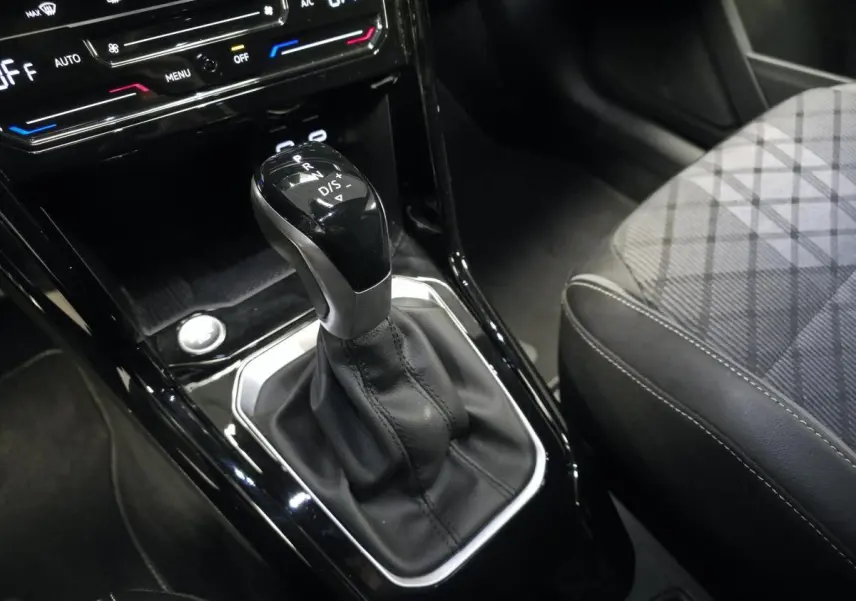 Le levier de vitesse automatique noir et argenté du Volkswagen T-Roc 1.5 TSI Evo R-Line, avec sellerie tissu gris à motifs.