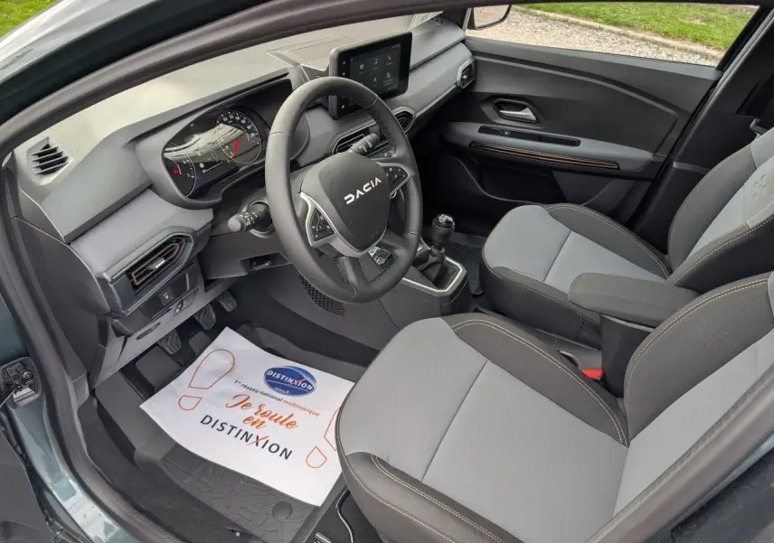 Vue intérieure côté conducteur du Dacia Jogger gris métallisé, avec volant multifonction et sellerie bicolore gris et brun cuivré.