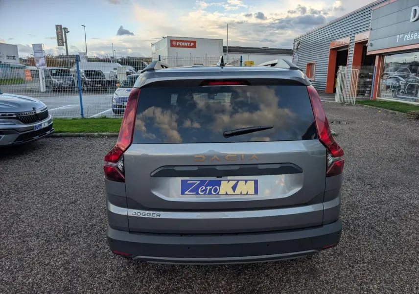 Vue arrière d’un Dacia Jogger gris métallisé avec logo brun cuivré et plaque Zéro KM visible.