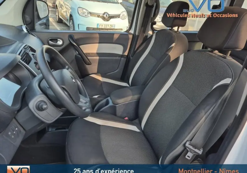 Intérieur avant du Renault Kangoo blanc 2016, sièges bi-ton noirs et gris, volant et tableau de bord visibles.