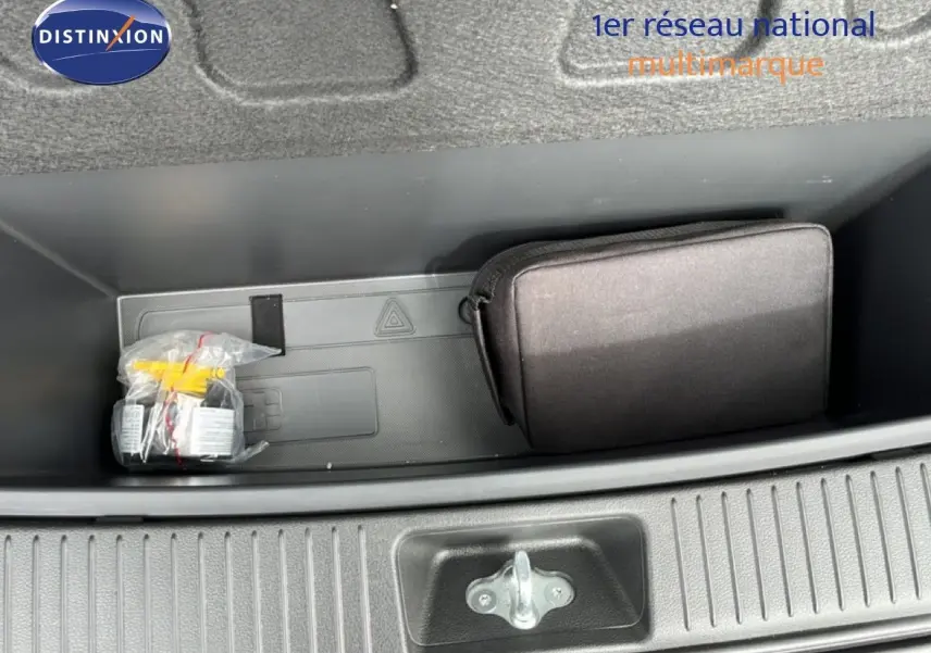 Coffre ouvert vu de dessus montrant un rangement avec une trousse noire et un kit emballé dans une Hyundai i30 SW rouge.