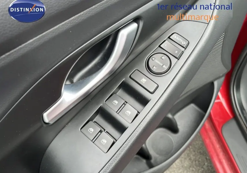 Gros plan sur la commande des vitres et rétroviseurs côté conducteur d'une Hyundai i30 SW rouge 2023.