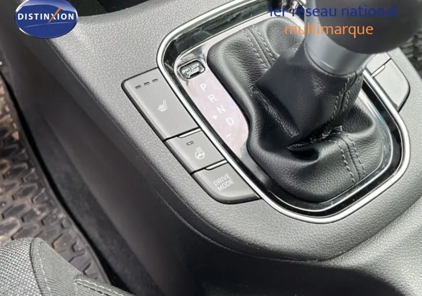 Gros plan sur la console centrale noire de la Hyundai i30 SW 2023, mettant en valeur le levier de vitesse automatique et les boutons chauffants.