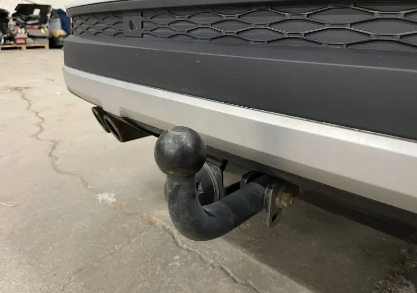 Gros plan sur l'attelage noir fixé au pare-chocs arrière blanc du SEAT Ateca 2016, en intérieur.