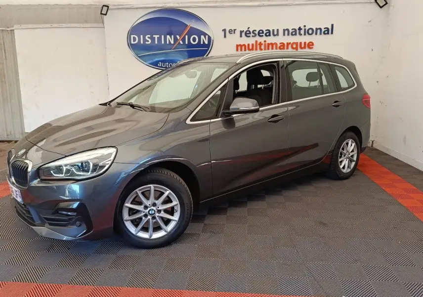 BMW Série 2 Gran Tourer gris clair vue 3/4 avant droit, avec jantes alliage et feux LED allumés.