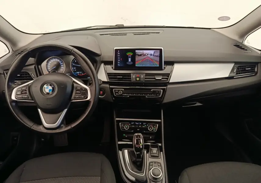 Vue intérieure avant de la BMW Série 2 Gran Tourer 218i Lounge 2022, tableau de bord noir avec écran central et volant cuir alu.