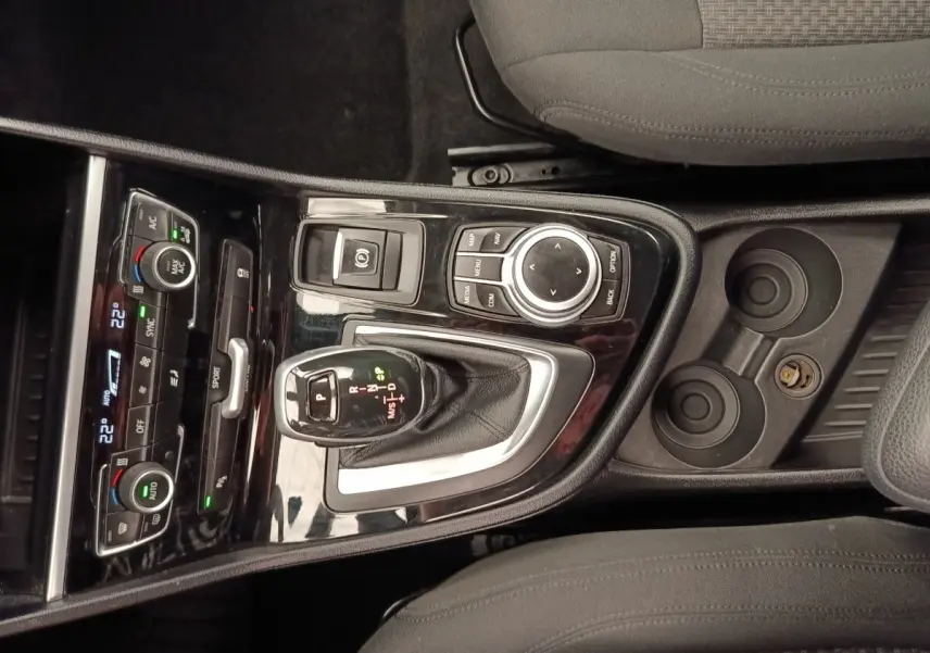 Vue plongeante sur la console centrale noire brillante de la BMW Série 2 Gran Tourer avec levier de vitesse automatique et commandes climatisation.