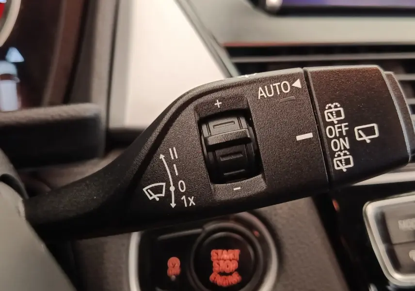Gros plan sur la commande des essuie-glaces à gauche du volant dans l’habitacle d’une BMW Série 2 Gran Tourer gris clair.