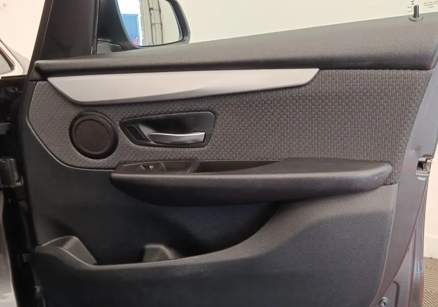 Vue rapprochée de la porte avant gauche de la BMW Série 2 Gran Tourer gris clair, avec garniture tissu et poignée alu.