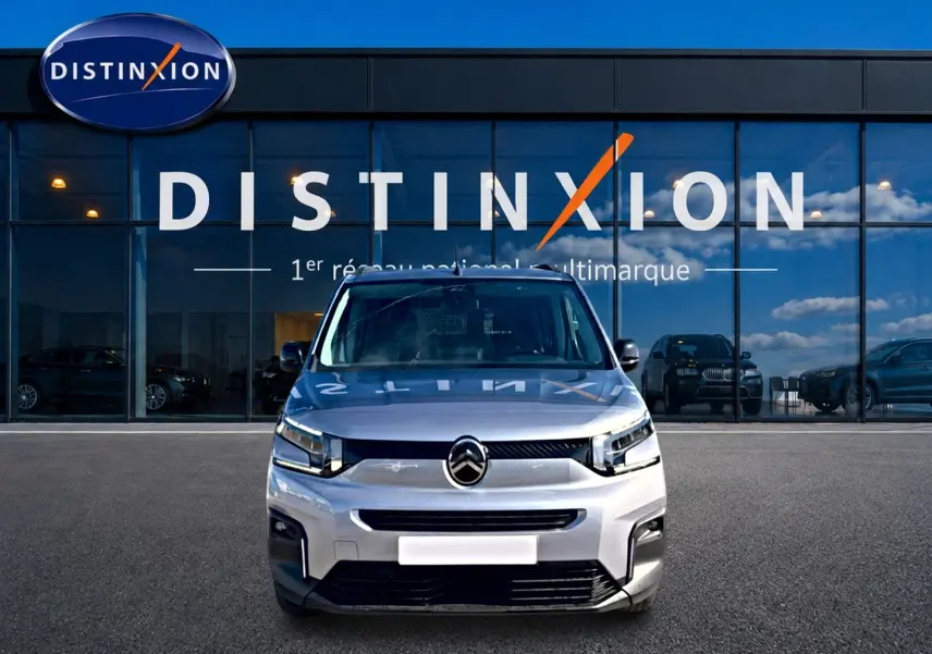 Vue avant d'un Citroën Berlingo 2026 gris acier, avec calandre moderne et phares LED devant un showroom Distinxion.