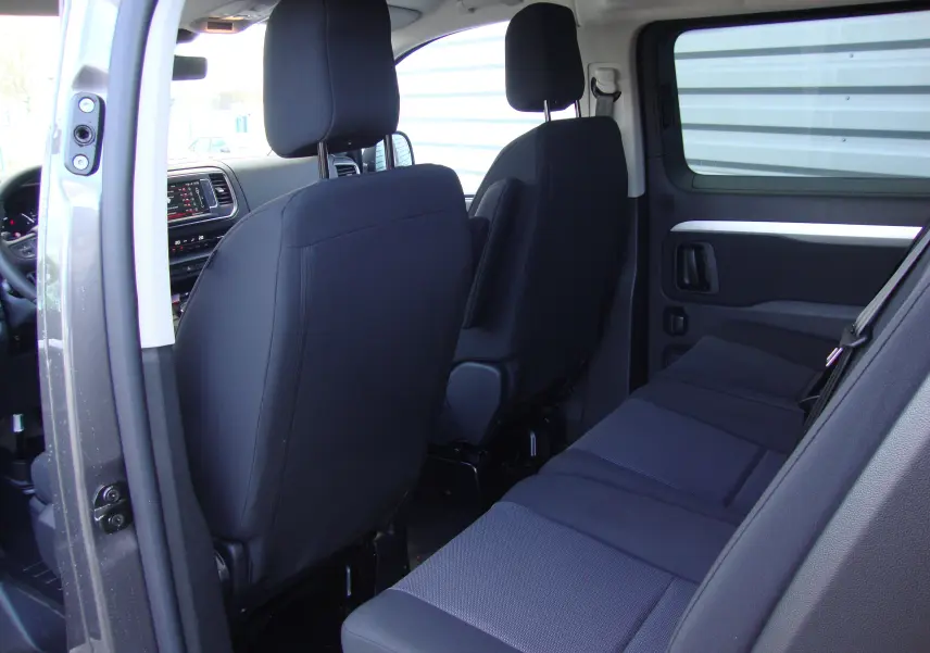 Vue intérieure côté droit du Citroën Jumpy XL gris platinum, montrant les sièges arrière et avant en tissu noir.