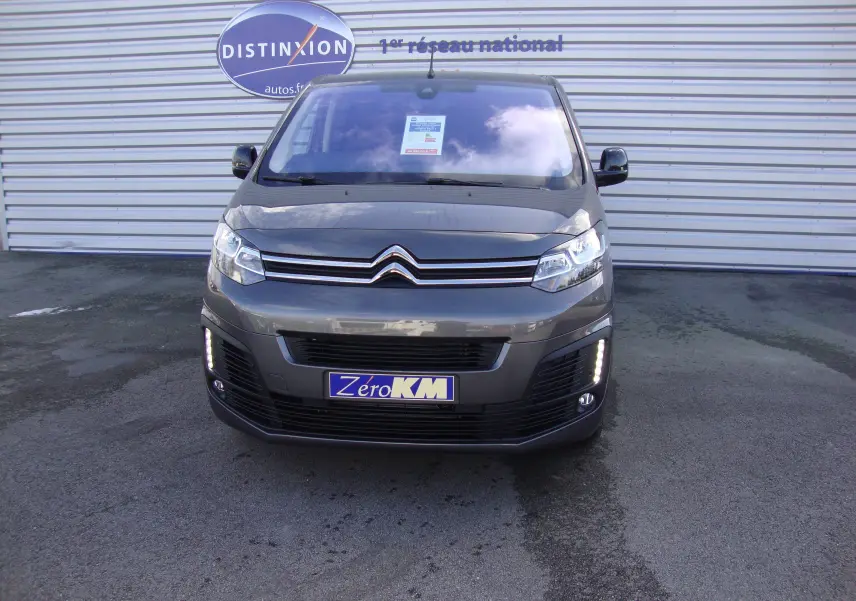 Vue frontale d'un Citroën Jumpy Cabine Approfondie gris platinum avec feux diurnes LED allumés sur un parking.