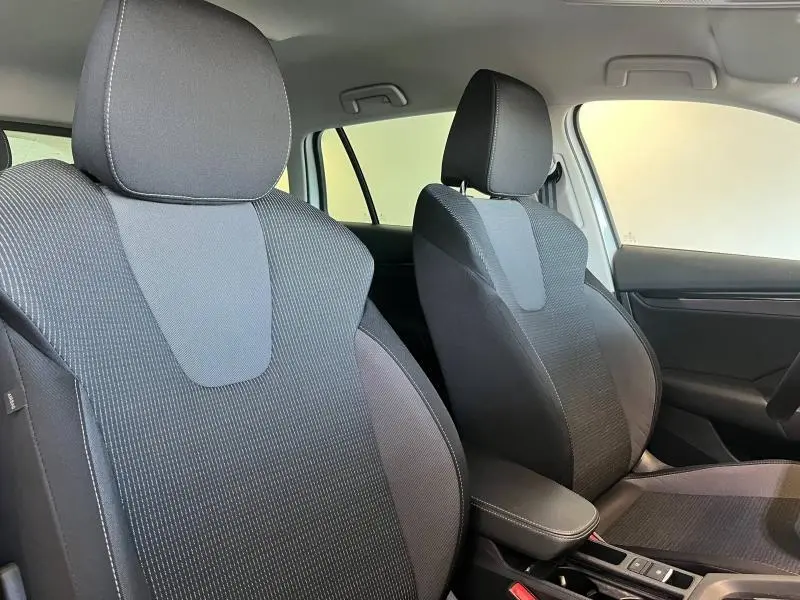 Gros plan sur les sièges avant en tissu noir de la Skoda Octavia Combi 2022, avec accoudoir central visible.