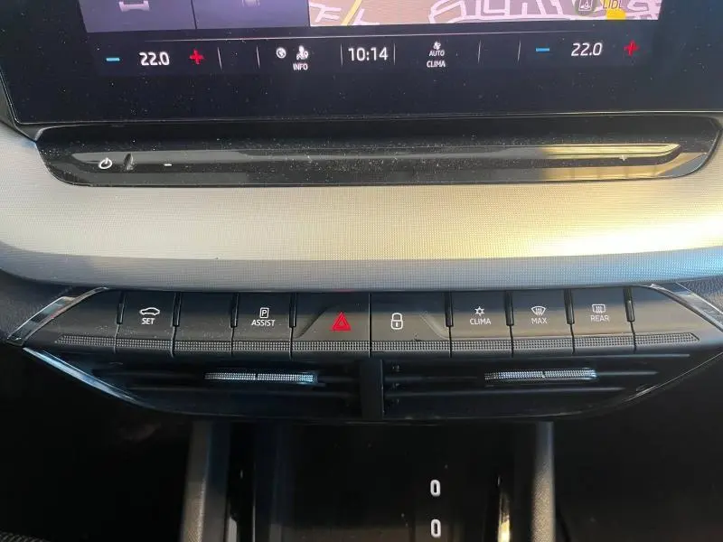 Vue rapprochée de la console centrale de la Skoda Octavia Combi blanche, avec commandes climatisation et boutons fonctionnels.