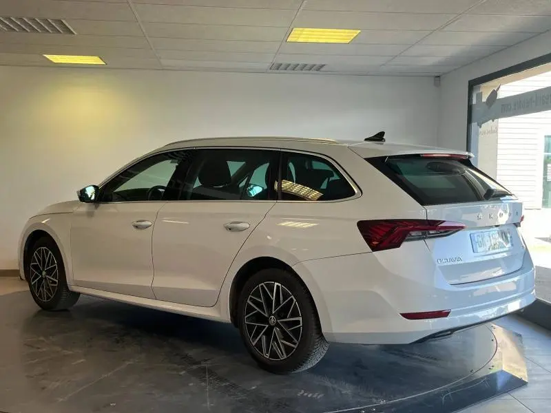 Vue de profil côté gauche d'une Skoda Octavia Combi blanche Cristal spéciale, avec jantes alu et feux arrière LED visibles.