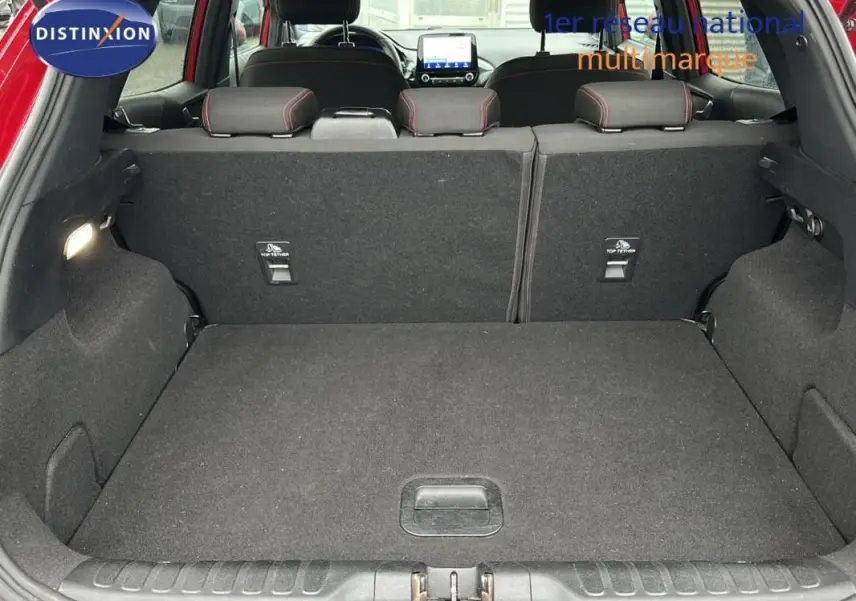 Coffre ouvert d'un Ford Puma rouge 2020, vue arrière montrant l'espace de chargement et les sièges arrière rabattus.