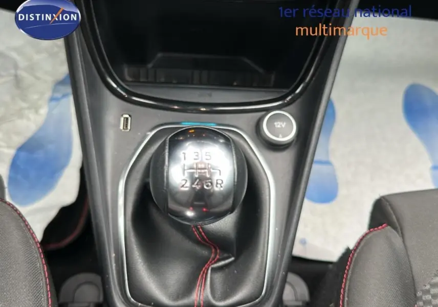 Gros plan sur le levier de vitesses manuel du Ford Puma rouge 2020 avec surpiqûres rouges et prise 12V.