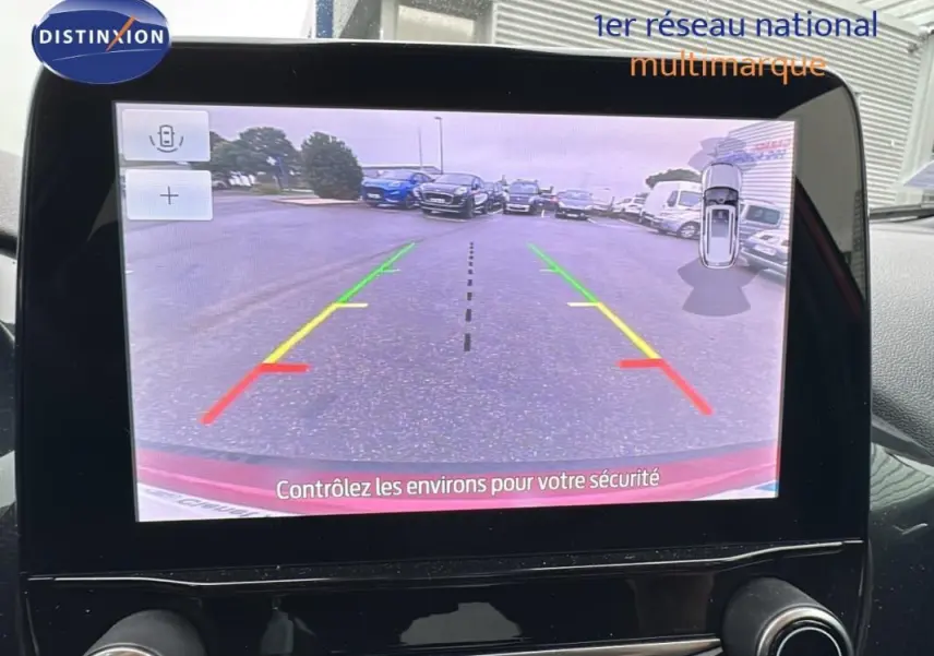 Écran tactile du Ford Puma rouge montrant la caméra de recul avec lignes de guidage colorées en extérieur.