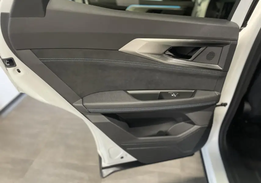 Porte arrière gauche ouverte du Renault Austral blanc nacré satin, garniture noire avec surpiqûres bleues et insert aluminium.
