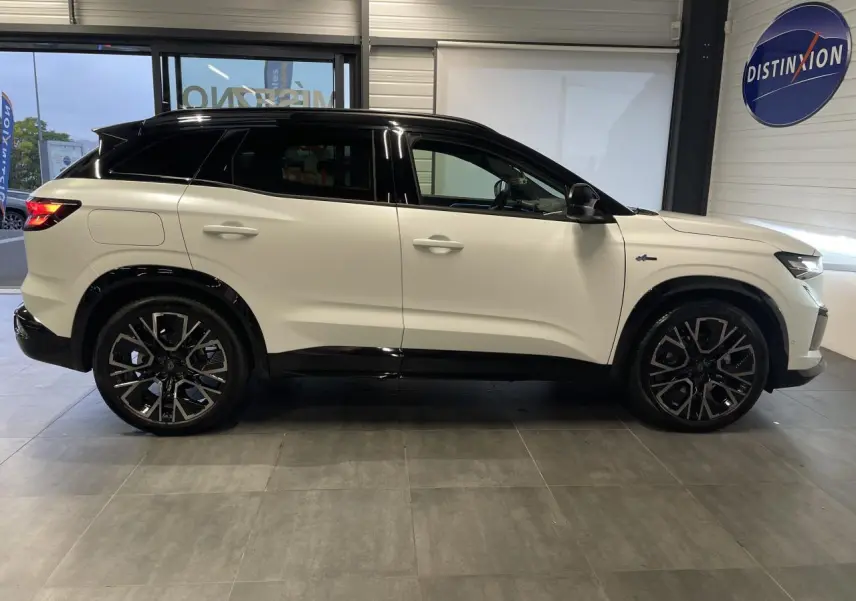 Profil droit du Renault Austral 2025 blanc nacré satin avec toit noir et jantes alliage noires en showroom.