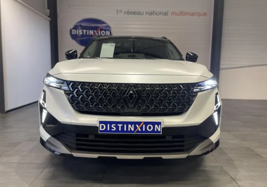 Vue frontale d'un Renault Austral blanc nacré satin avec calandre noire et feux LED allumés en showroom.