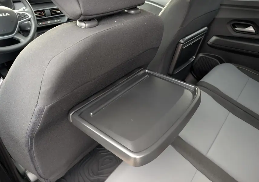Vue intérieure arrière droite du Dacia Jogger 2025, avec tablette rabattable sur le dossier du siège avant et sellerie bicolore.