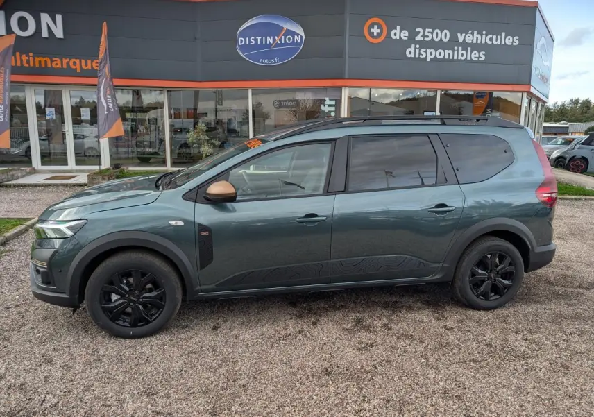 Vue latérale droite d'un Dacia Jogger 2025 vert métallisé avec jantes noires et rétroviseurs cuivrés.
