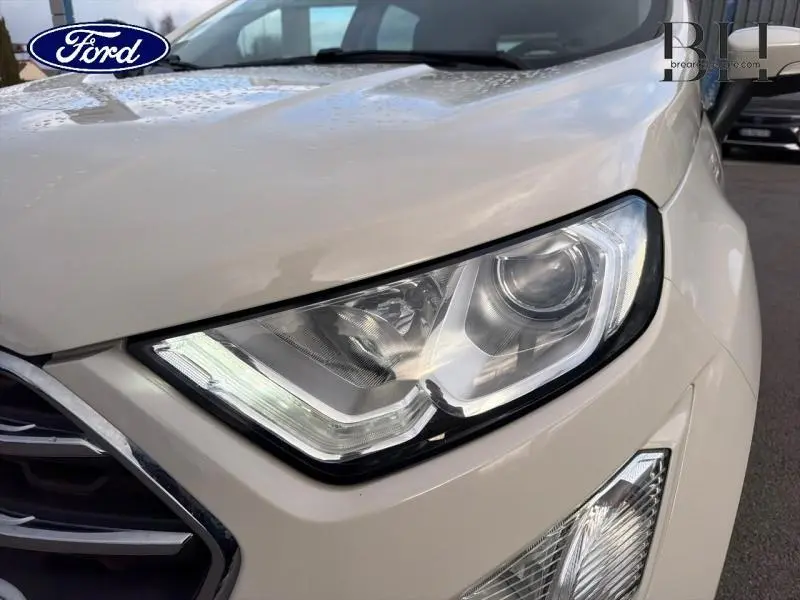 Gros plan sur le phare avant droit du Ford EcoSport 2020 blanc Fashion Metropolis avec calandre chromée visible.