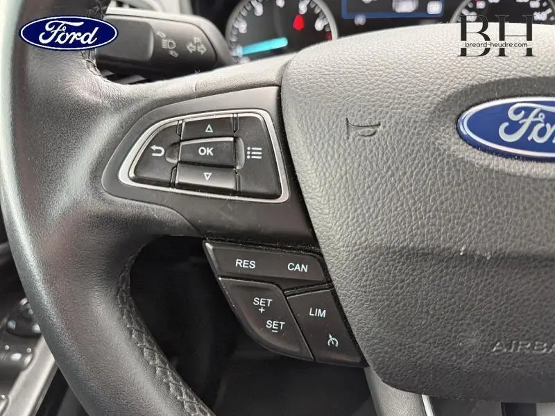 Gros plan sur le volant noir du Ford EcoSport 2020 avec commandes multifonctions et logo Ford central.