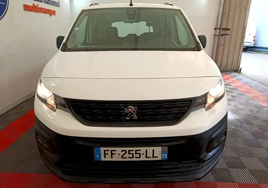 Vue de face d’un Peugeot Rifter blanc 2019 avec calandre noire et phares allumés en intérieur.