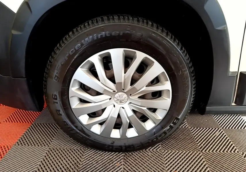 Gros plan sur la roue avant gauche du Peugeot Rifter blanc, avec jante en alliage et pneu hiver visible.