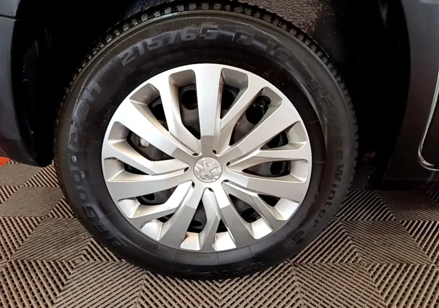 Gros plan sur la roue avant droite du Peugeot Rifter blanc, mettant en valeur la jante argentée et le pneu hiver Goodyear.