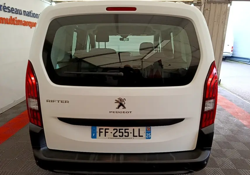 Vue arrière du Peugeot Rifter blanc de 2019 avec hayon vitré et feux arrière verticaux rouges.