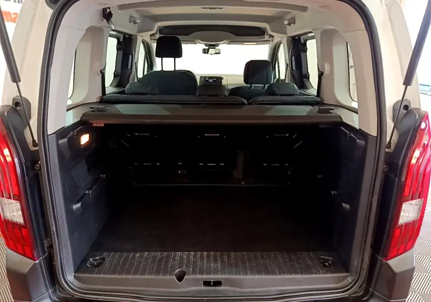 Vue arrière ouverte du coffre spacieux du Peugeot Rifter blanc 2019, avec banquette arrière et tablette cache-bagages visibles.