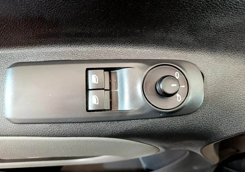 Gros plan sur les commandes de réglage des rétroviseurs et des vitres électriques côté conducteur du Peugeot Rifter blanc.