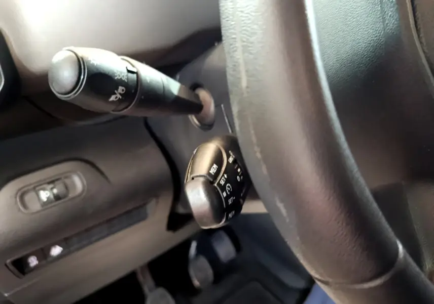 Gros plan sur la colonne de direction et les commandes derrière le volant du Peugeot Rifter blanc, version PureTech 110 S&S Active.