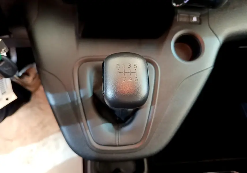 Le levier de vitesses manuel noir en gros plan dans l'habitacle du Peugeot Rifter blanc, vue centrée dessus.