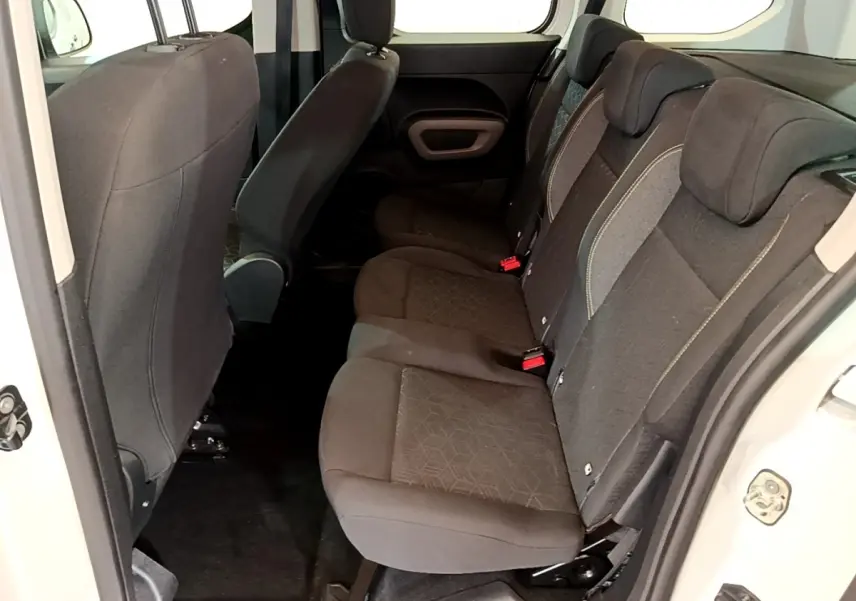 Vue intérieure côté droit sur la banquette arrière noire du Peugeot Rifter blanc, montrant les sièges et appuie-têtes.