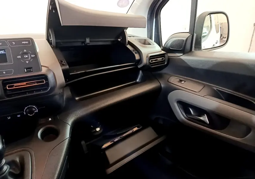 Intérieur côté passager du Peugeot Rifter blanc 2019, avec boîte à gants ouverte et tableau de bord visible.