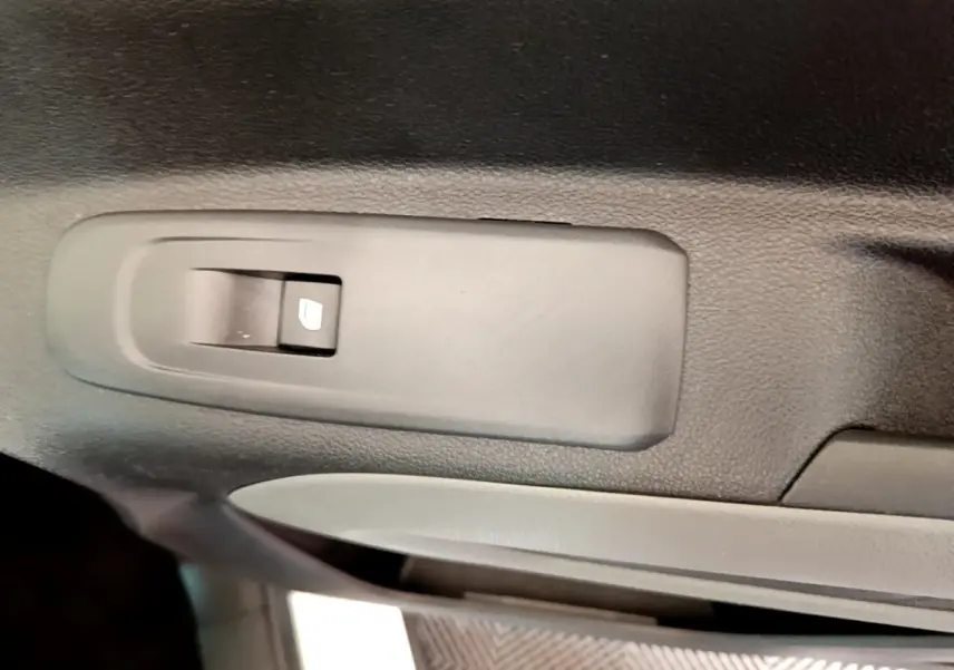Gros plan sur le bouton de commande de lève-vitre côté gauche intérieur d’un Peugeot Rifter blanc 2019.